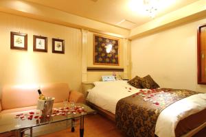 a hotel room with a bed and a table with roses on it at Restay Fuchu (Adult Only) in Fuchu