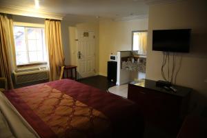 Habitación de hotel con cama y TV de pantalla plana. en Chateau Inn & Suites en Downey