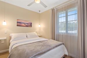 a white bedroom with a bed and a window at Hamptons at The Bay in Deception Bay