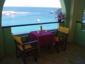 a table with chairs and a bottle of wine and a view of the ocean at Haravgi Hotel in Patitiri