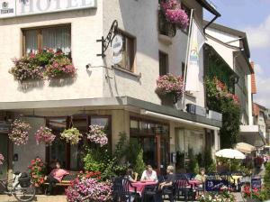 um grupo de pessoas sentadas em mesas fora de um hotel em Gasthof Hausmann em Schlüchtern