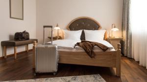 ein Schlafzimmer mit einem Bett mit einem Koffer in der Unterkunft Romantik Hotel Schubert in Lauterbach