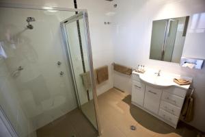 a bathroom with a shower, sink, and mirror at Cattlemans Country Motor Inn & Serviced Apartments in Dubbo