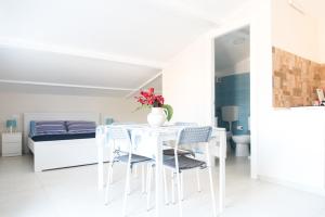 a white dining room with a white table and chairs at Casa Vacanze Albora in Punta Secca