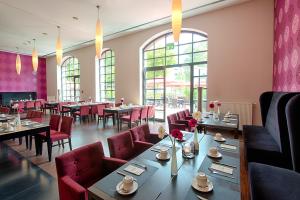 un comedor con mesas, sillas y ventanas en ACHAT Hotel Offenbach Plaza, en Offenbach