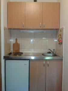 a small kitchen with wooden cabinets and a sink at Apartments Mrvaljevic in Petrovac na Moru