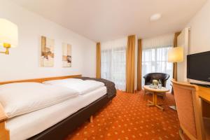 a hotel room with a bed and a flat screen tv at Hotel Garni Gästehaus am Mühlbach in Ottobeuren