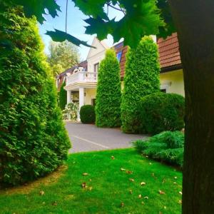 a house with bushes and trees in front of a yard at Noce i Dnie Hotel in Konstancin-Jeziorna