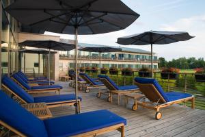 un groupe de chaises et de parasols sur une terrasse dans l'établissement Hôtel Barrière Ribeauvillé, à Ribeauvillé