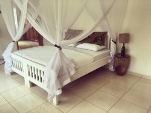 ein Schlafzimmer mit einem weißen Bett mit Baldachin in der Unterkunft The Guinea Fowl in Entebbe