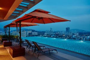 a swimming pool with chairs and a red umbrella at Sunway Velocity Hotel Kuala Lumpur in Kuala Lumpur