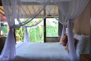 - une chambre avec un lit à baldaquin dans l'établissement Griya Sriwedari, à Ubud