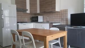 a kitchen with a wooden table and white chairs at Alba Appartamenti in Sottomarina
