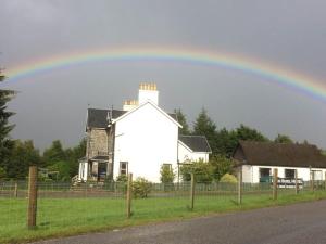 a rainbow over a white house in a field at Loch Shiel Hotel in Acharacle