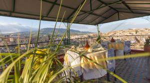 einen Balkon mit Tischen und Stadtblick in der Unterkunft Riad El Bacha in Fès