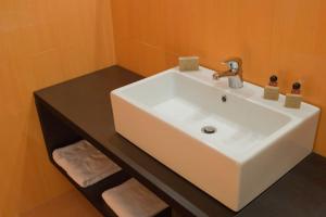 a white sink in a bathroom with an orange wall at Hotel Gio in Arad