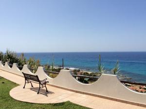 a bench sitting on a walkway next to the ocean at Residenza Stefanelli in Capo Vaticano