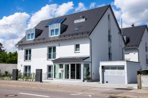 ein weißes Haus mit einem schwarzen Dach in der Unterkunft Pension Sonntag in Ingolstadt