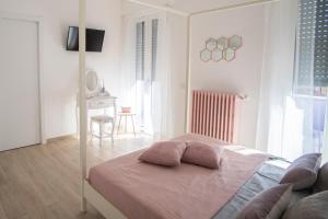 a white bedroom with a bed with pink pillows on it at La Maison Extravagante in Saronno