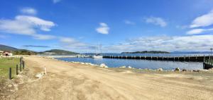 a dirt road next to a body of water with boats at Manfield Seaside Bruny Island in Alonnah