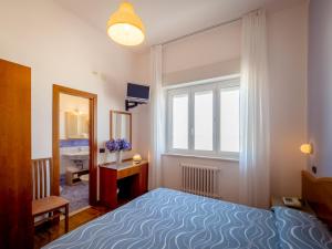 Schlafzimmer mit einem Bett, einem Fenster und einem Spiegel in der Unterkunft Hotel de la Ville in Senigallia