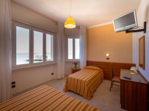 ein Hotelzimmer mit einem Bett und einem TV in der Unterkunft Hotel de la Ville in Senigallia