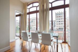 a dining room with a table and chairs and large windows at Tendency Rambla Catalunya in Barcelona