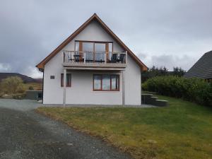 a white house with a balcony on top of it at Lochview Chalet in Eyre