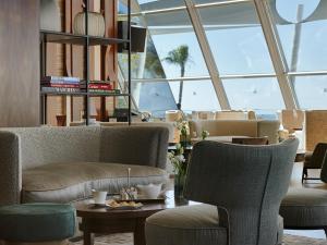a lobby with chairs and tables and windows at Amathus Beach Hotel Limassol in Limassol