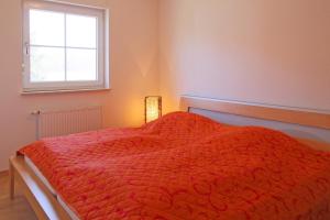 UmmanzにあるFerienhaus Lüßvitzのベッドルーム1室(赤い掛け布団、窓付)
