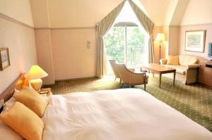 那須町にあるホテル・フロラシオン那須のベッドとリビングルームが備わるホテルルームです。