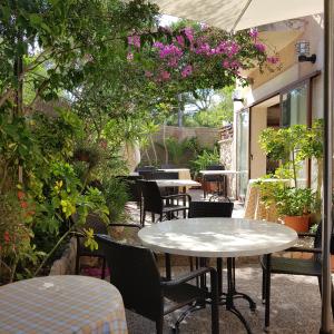 un patio al aire libre con mesas, sillas y flores en Villa Lorenzo, en Cala Figuera