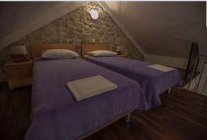 zwei Betten in einem Schlafzimmer im Dachgeschoss mit lila Laken in der Unterkunft Apartments Punta in Starigrad-Paklenica