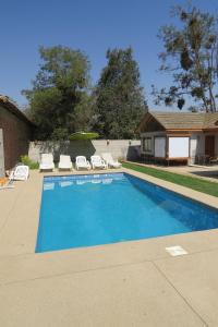 uma piscina com cadeiras e uma casa em Cabañas Vikurayen em Olmué