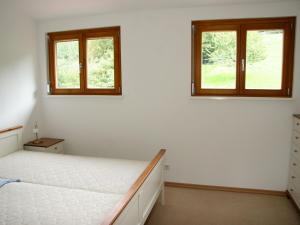 a bedroom with a bed and two windows at Haus am Gunzenbach in Baden-Baden