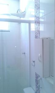 y baño blanco con ducha y aseo. en Quitinete Cabo Frio, en Cabo Frío