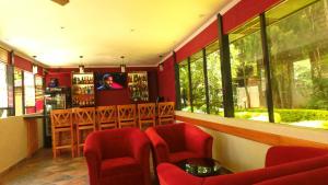 un restaurante con sillas rojas y un bar con ventanas en The Noble Hotel & Conference Centre en Eldoret