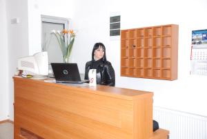 a woman sitting at a desk with a laptop at M Garni Hotel in Vranje