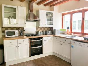 a kitchen with white cabinets and a stove top oven at Highwood Lodge in Scissett