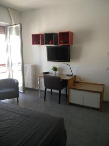 Habitación con escritorio, TV y mesa con silla. en B&B Via Roma 15 en Acquaviva delle Fonti