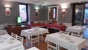 ein Restaurant mit weißen Tischen und Stühlen sowie einem TV in der Unterkunft Logis L'Auberge Bourbonnaise in Saint-Yorre