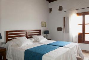 um quarto com uma cama com um cobertor azul e branco em Caserío Leandro III em Mácher