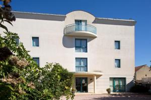 Großes weißes Gebäude mit Balkon in der Unterkunft Logis L'Auberge Bourbonnaise in Saint-Yorre