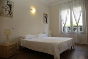 a white bedroom with a bed and a window at Plage du Midi in Cannes