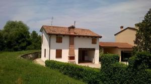 a small white house sitting on top of a green field at La Campagnola - Casa Vacanze in Torri di Quartesolo