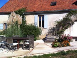 a patio with a table and chairs in front of a house at Le Petit Savriere B&B in Tronget