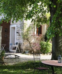 stół i krzesła pod drzewem na dziedzińcu w obiekcie La Poussiniere w mieście Auvers-Saint-Georges