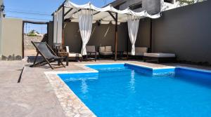 a blue swimming pool with a umbrella and a patio at Casagrande Hotel de Adobe in Tinogasta +108 photos