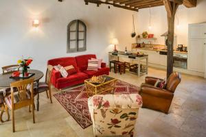a living room with a red couch and a kitchen at Maison le Village - Maison d’Hôtes in Montagny-lès-Beaune