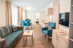 ein Wohnzimmer mit einem Sofa und blauen Stühlen in der Unterkunft AKZENT Apartmenthotel Residenz in Graal-Müritz